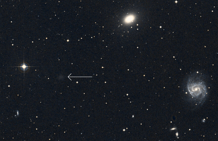 NGC 1052-DF2 (arrowed) can barely be seen in earlier images (like in this one from the Digitized Sky Survey), and it's easy to overlook. Credit: Simbad / Aladin