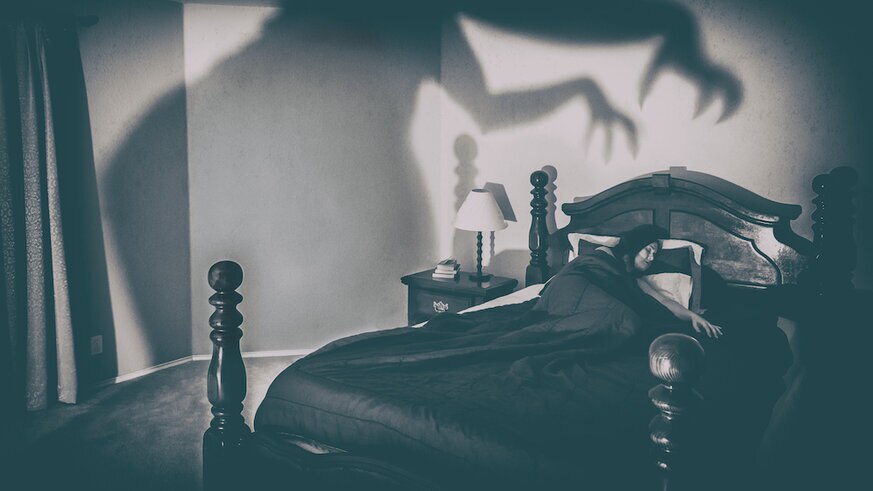 Woman Sleeping On Bed With Spooky Shadow On Wall