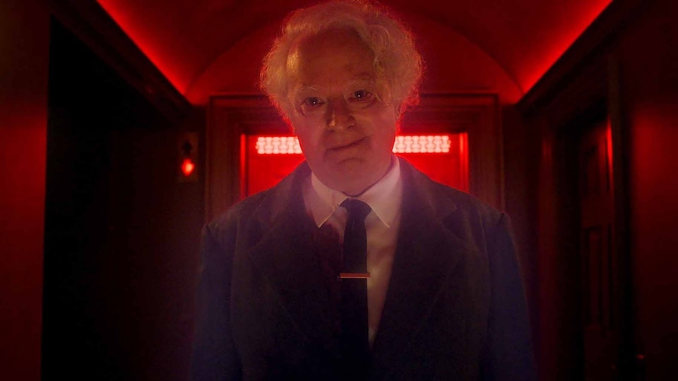 Charles Lee Ray (Brad Dourif) stands in a red-lit hallway in Chucky Episode 306.