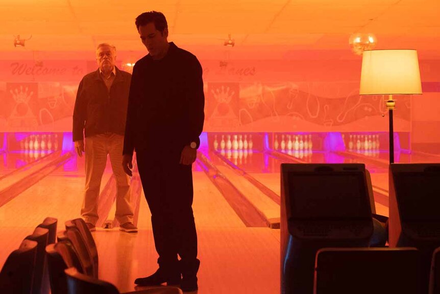 (l-r) Carl Roman (Art Hindle) watches Luke Roman (Tim Rozon) in an orange bowling alley in SurrealEstate 210
